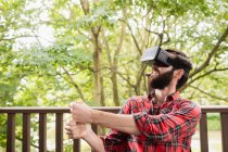 Hombre usando auriculares de realidad virtual en la terraza del bar - foto de stock