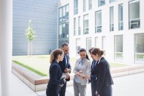 Business people discussing over digital tablet outside office building — Stock Photo