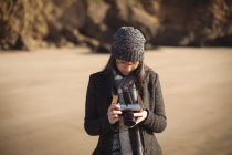 Жінка дивиться фотографії на цифрову камеру на пляжі вдень — стокове фото