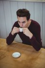 Homem tomando café enquanto sentado em uma cafeteria — Fotografia de Stock