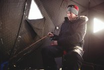 Pêcheur sur glace vérifiant canne à pêche dans la tente — Photo de stock