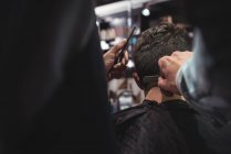 Homme se faire couper les cheveux par coiffeur avec rasoir dans le salon de coiffure — Photo de stock