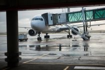 Puente de embarque atracado con avión en aeropuerto - foto de stock