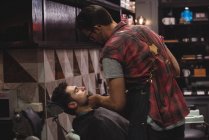 Man getting beard shaved in barbershop — Stock Photo