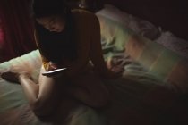 Mulher usando telefone celular na cama no quarto em casa — Fotografia de Stock