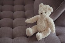 Orsacchiotto bianco sul divano di casa — Foto stock