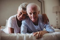 Retrato de feliz pareja de ancianos acostados en la cama en el dormitorio - foto de stock