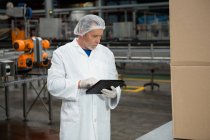 Ernsthafter männlicher Arbeiter mit digitalem Tablet in Kaltgetränkfabrik — Stockfoto