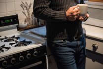 Середина человека, держащего чашку кофе дома — стоковое фото