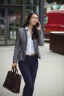 Businesswoman talking on mobile phone near office building — Stock Photo