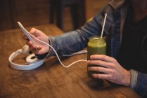 Середина людини, що використовує мобільний телефон, маючи сік у кафе — стокове фото