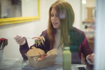 Рыжая женщина ест салат в ресторане — стоковое фото