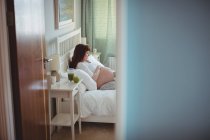 Schwangere entspannt sich auf Bett im Schlafzimmer — Stockfoto