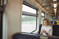 Rubia mediana mujer de negocios adulta utilizando el teléfono inteligente mientras viaja - foto de stock