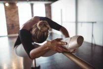 Ballerina che si allunga alla sbarra in studio di danza classica — Foto stock