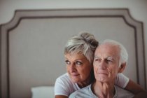 Senior woman embracing senior man on bed in bed room — Stock Photo