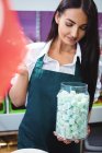 Ladenbesitzerin hält Glas mit türkischen Süßigkeiten am Ladentisch — Stockfoto