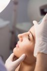 Mãos de médico examinando rosto feminino para tratamento cosmético na clínica — Fotografia de Stock