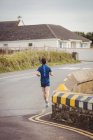 Вид сзади на человека, совершающего пробежку по открытой дороге — стоковое фото