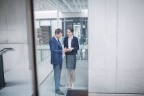 Homme d'affaires et collègue discuter sur tablette numérique à l'intérieur de l'immeuble de bureaux — Photo de stock