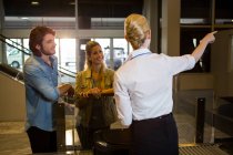 Pessoal feminino que guia os passageiros no terminal do aeroporto — Fotografia de Stock