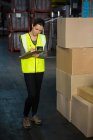 Full length of female worker noting on clipboard in warehouse — Stock Photo