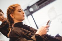 Красива жінка використовує мобільний телефон в салоні — стокове фото
