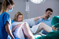 Врач осматривает беременную женщину во время родов в операционной — стоковое фото