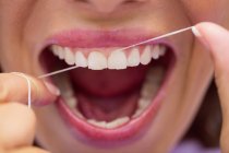 Close-up de pacientes do sexo feminino dentes fio dental na clínica odontológica — Fotografia de Stock