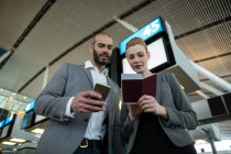Geschäftsleute mit Bordkarte und Mobiltelefon im Flughafenterminal — Stockfoto