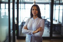 Портрет бізнес-леді, що стоїть з обіймами, схрещеними в офісі — стокове фото