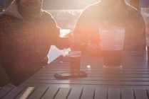 Чоловіки друзі мають келихи пива на гірськолижному курорті на яскравому сонячному світлі — стокове фото