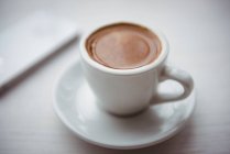 Primer plano de una taza de café sobre la mesa en la cafetería - foto de stock