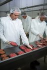 Metzger arbeiten in Fleischfabrik zusammen — Stockfoto