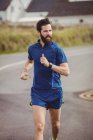 Handsome athlete running on the road — Stock Photo