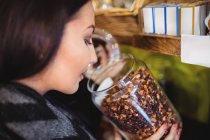Close-up of beautiful woman smelling jar of spices in shop — Stock Photo