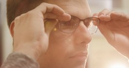 Close-up do cliente masculino vestindo óculos na loja óptica — Fotografia de Stock