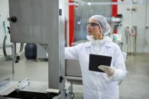 Female technician maintaining record on digital tablet at meat factory — Stock Photo