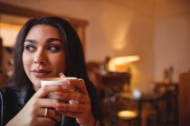 Удумлива жінка з чашкою кави в кафе — стокове фото