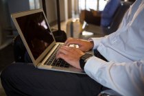 Man with luggage using laptop in waiting area at airport terminal — Stock Photo