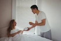Homem servindo café da manhã para mulher no quarto em casa — Fotografia de Stock