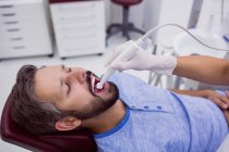 Primer plano del paciente con boca abierta sometido a chequeo dental en clínica dental - foto de stock
