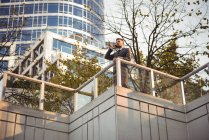 Businessman talking on mobile phone near office building — Stock Photo