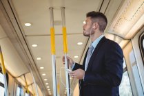 Бізнесмен слухає музику і використовує на мобільному телефоні в поїзді — стокове фото