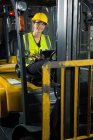 Portrait of female worker with digital tablet in forklift at warehouse — Stock Photo