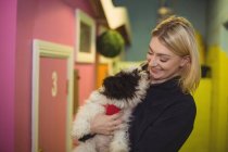 Весела жінка, що носить собаку-папіона в центрі догляду за собаками — стокове фото