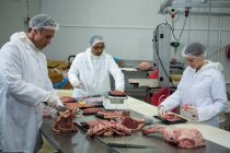 Мясники режут мясо на мясокомбинате — стоковое фото