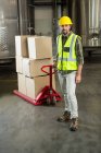 Full length portrait of male worker pulling trolley in warehouse — Stock Photo