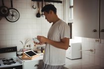 Людина сніданку дивлячись на цифровий планшетний кухні в домашніх умовах — стокове фото