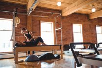 Treinador ajudando a mulher enquanto pratica pilates no estúdio de fitness — Fotografia de Stock